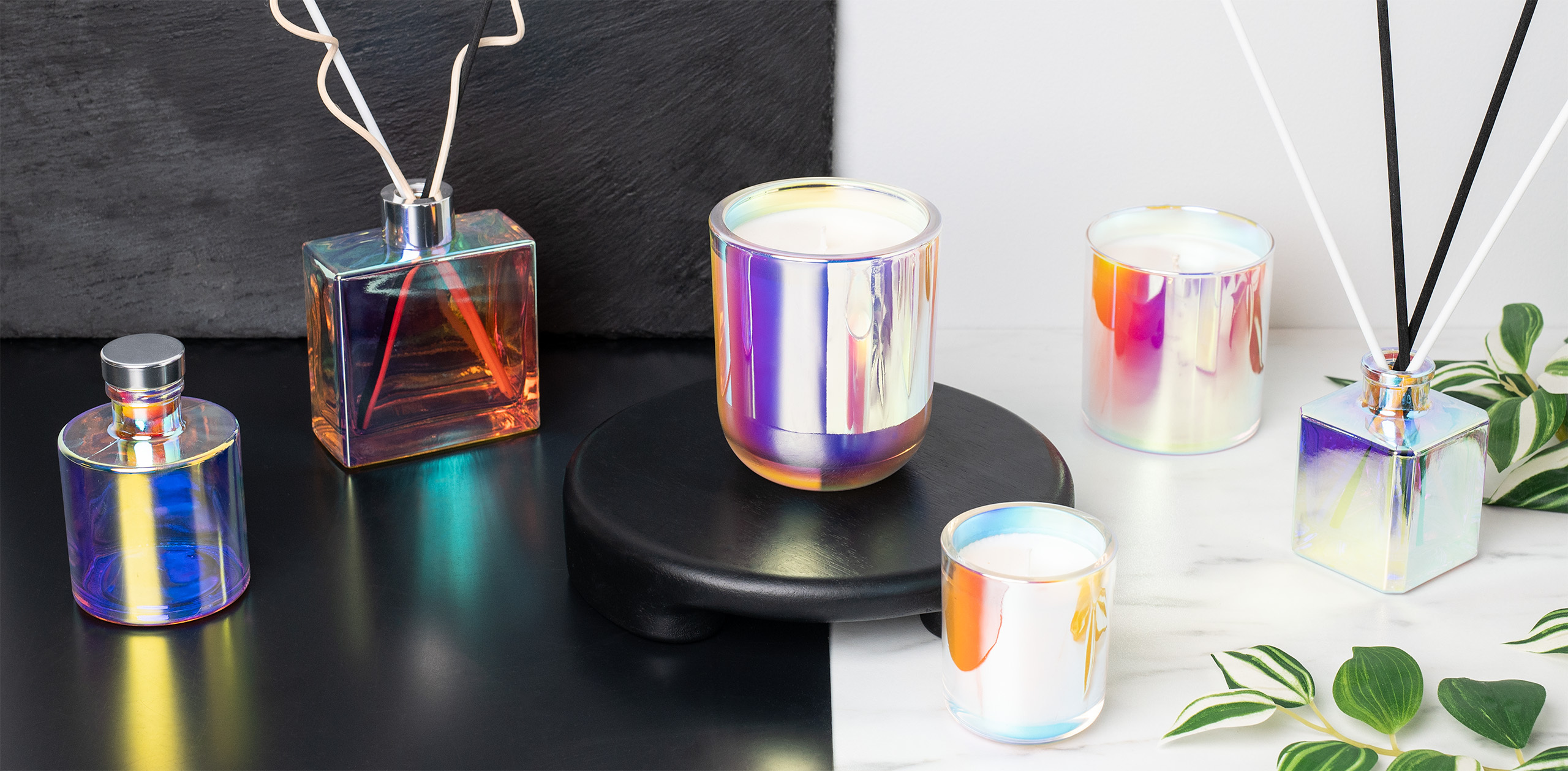 Iridescent containers for reed diffusers and candle making on a half white and half black background showcasing the difference in color on the containers. 